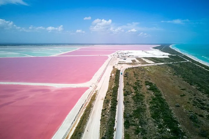 Luftaufnahme großer leuchtend rosa Salzseen, getrennt durch unbefestigte Wege.